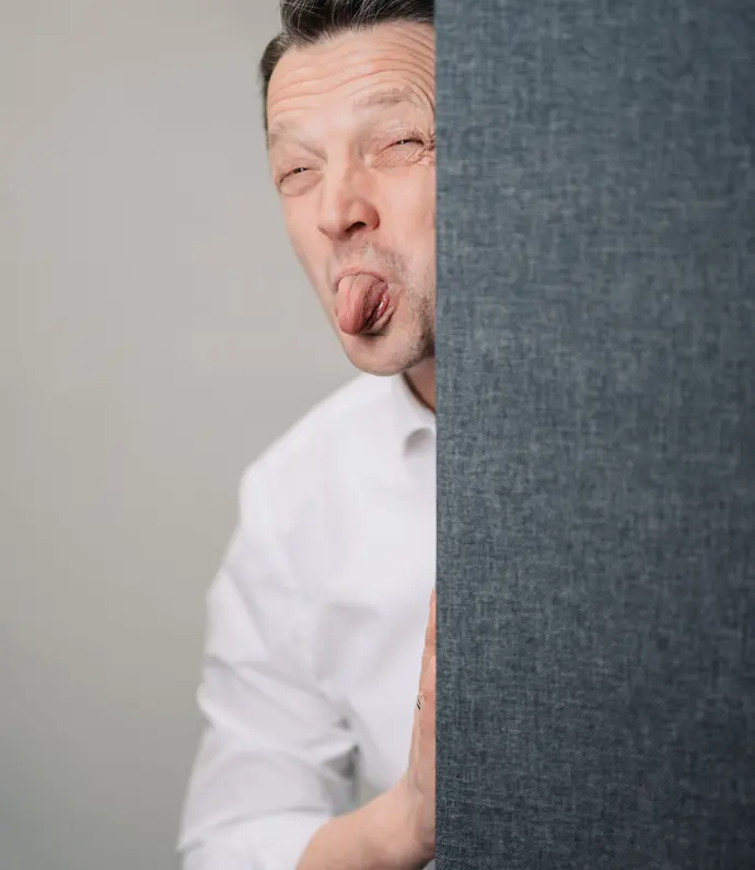 Ewald Janska schaut um die Ecke und streckt spielerisch die Zunge raus, zeigt seine humorvolle Seite.