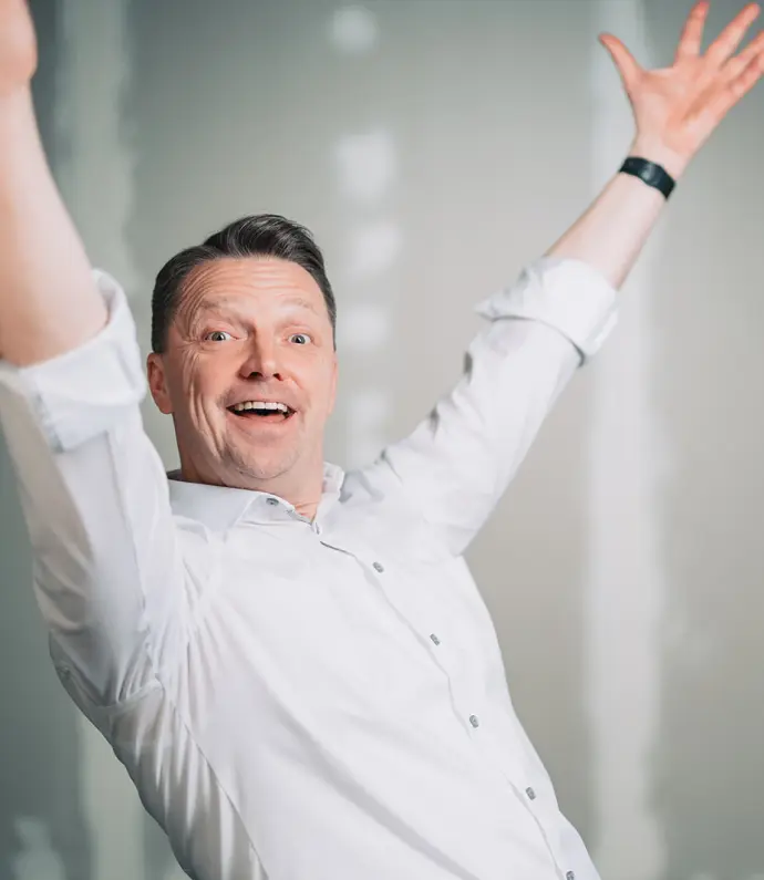 Ewald Janska lächelt in die Kamera und wirft die Arme nach oben, voller Energie und Freude.