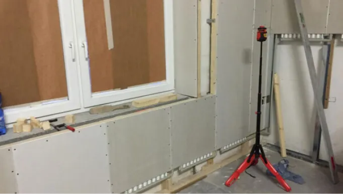 Rigipsplatten und abgedeckte Fenster für sicheren Einbau der Wandheizung im Trockenausbau.